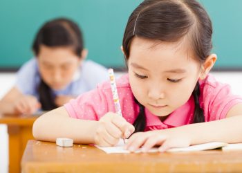 children in classroom with pen in hand